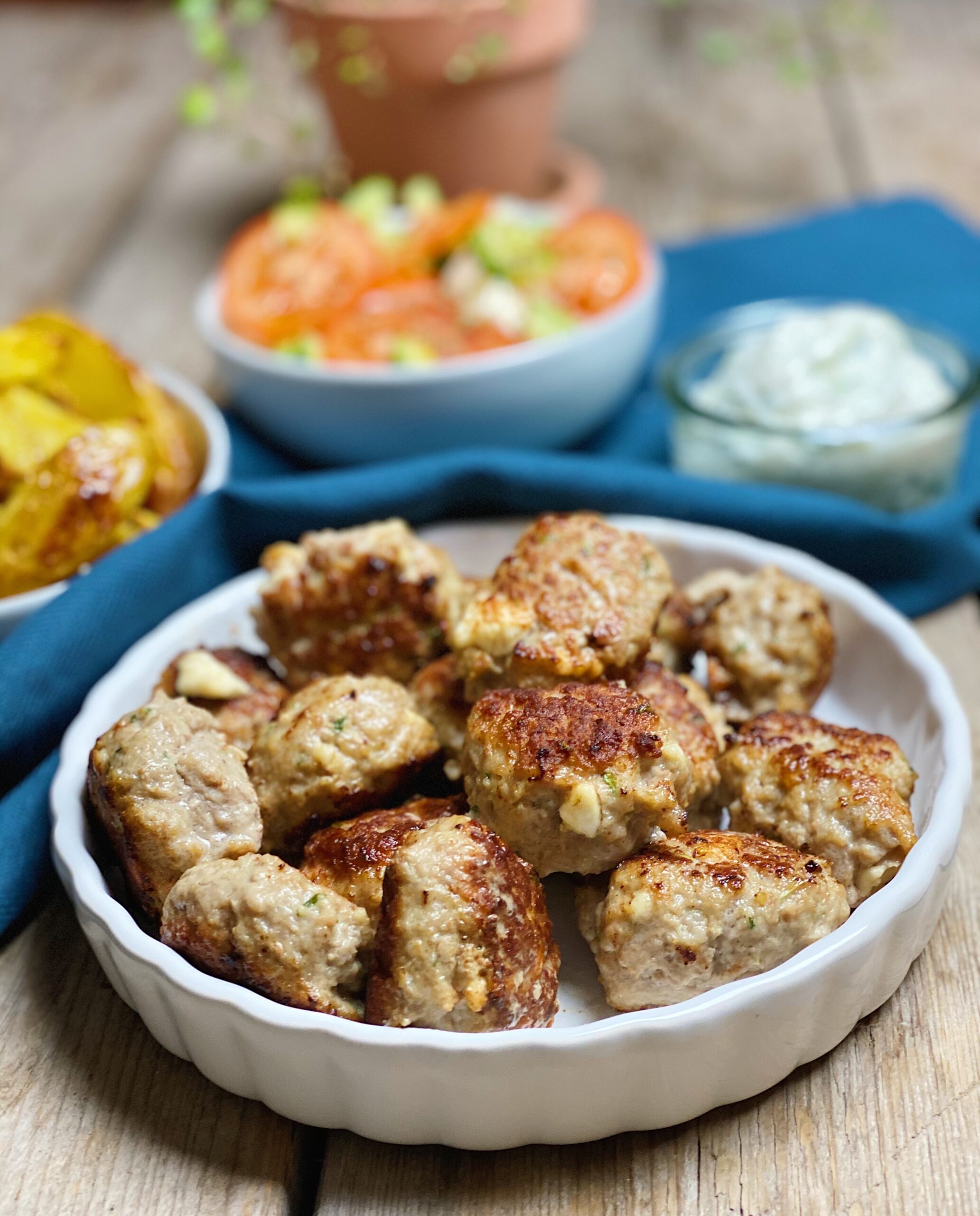 Græske frikadeller serveret med kartfoffelbåde, tomatsalat og tzatziki