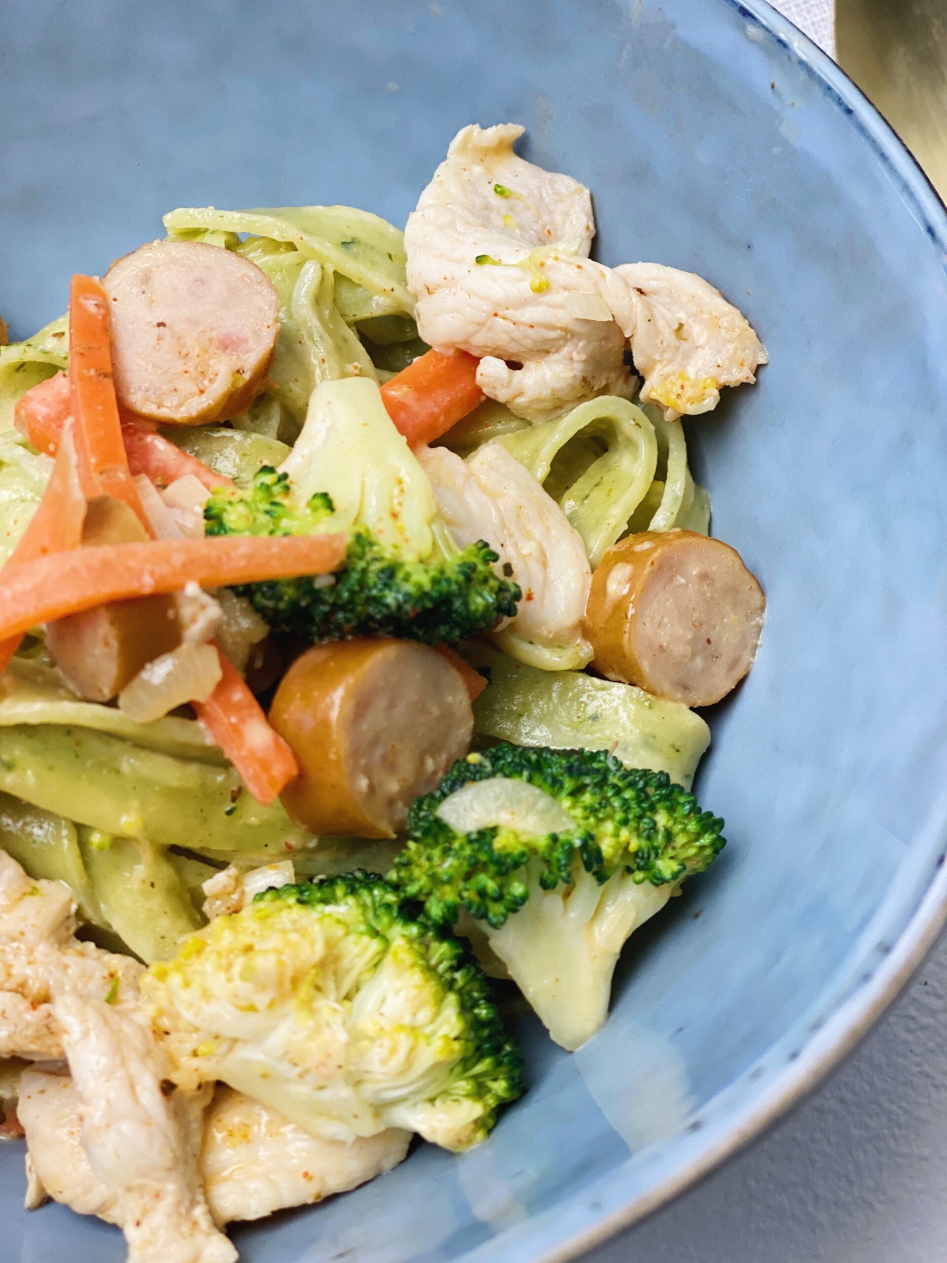 cremet spinatfettuccine med kylling og pølser tæt på