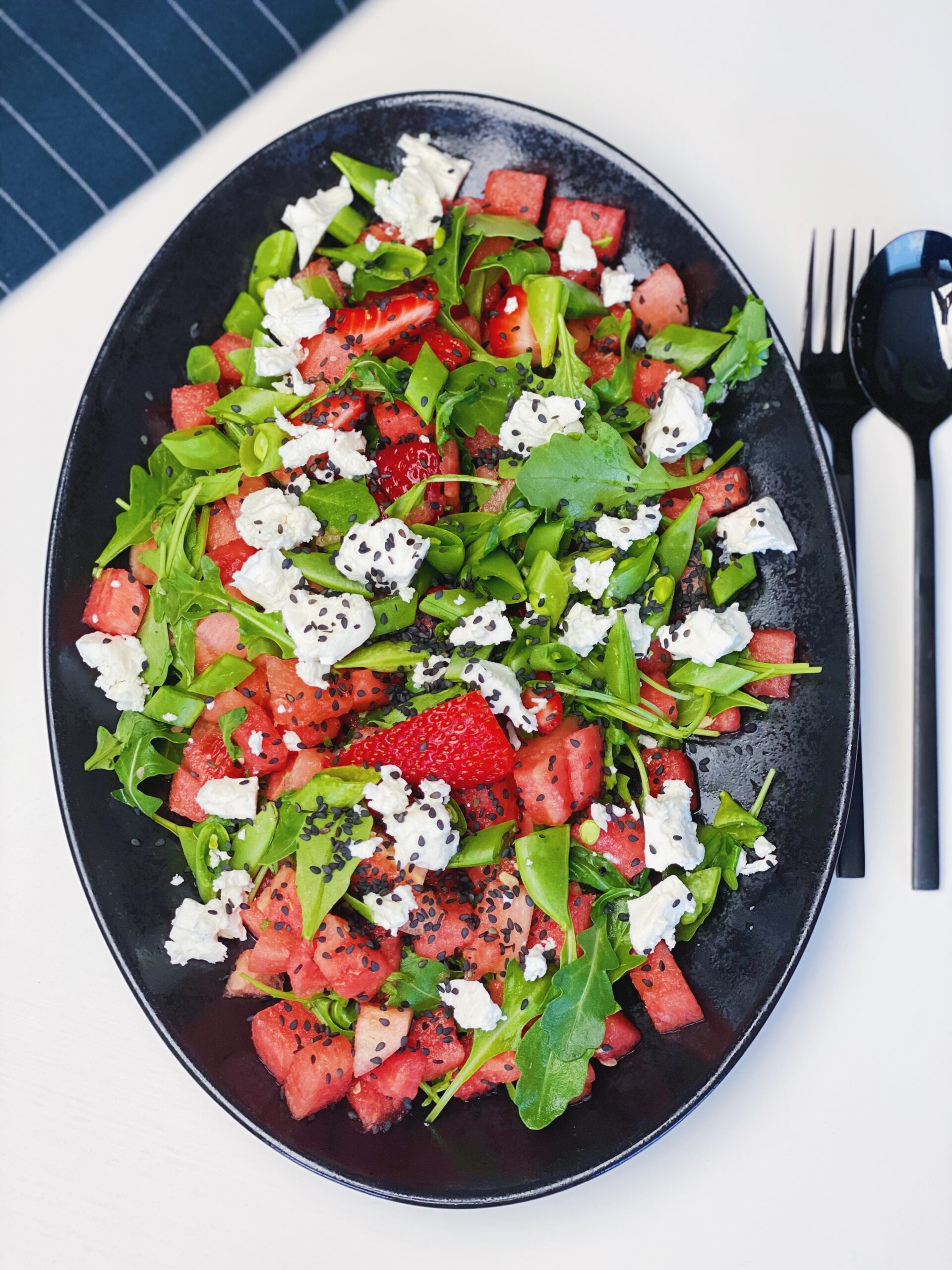 Sommersalat med vandmelon og jordbær på et sort fad