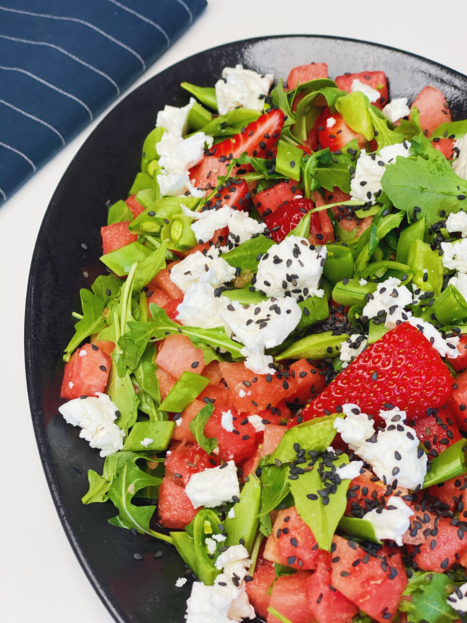 Sommersalat med vandmelon og jordbær på et sort fad