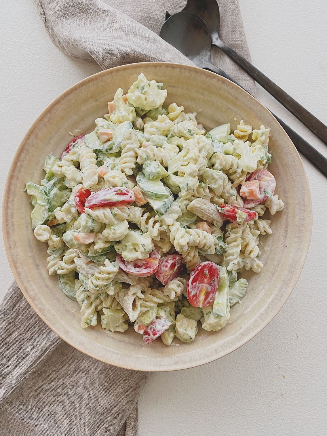 Pastasalat med masser af grønt og krydderurtedressing i en skål set oppefra