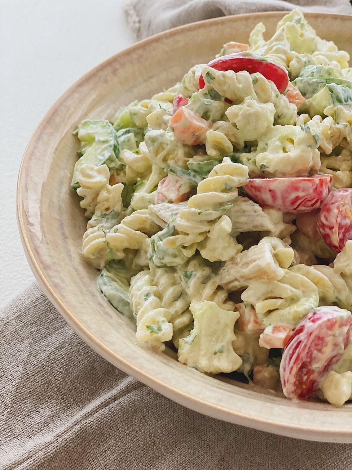 Pastasalat med masser af grønt og krydderurtedressing i en skål set tæt på