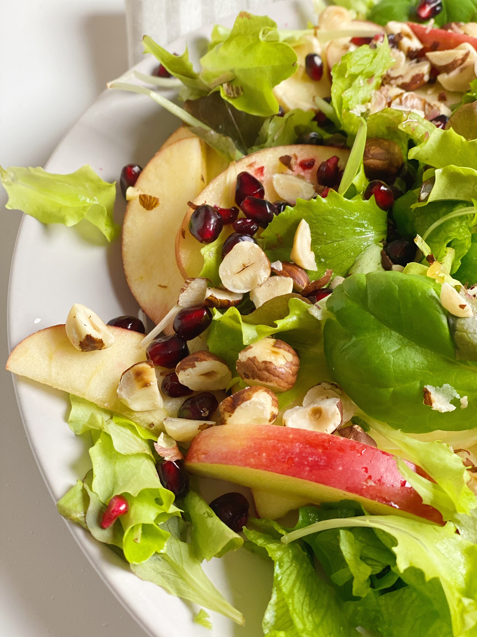 Salat med appelsinvinaigrette set meget tæt på, hvor man kun kan se halvdelen af tallerkenen.