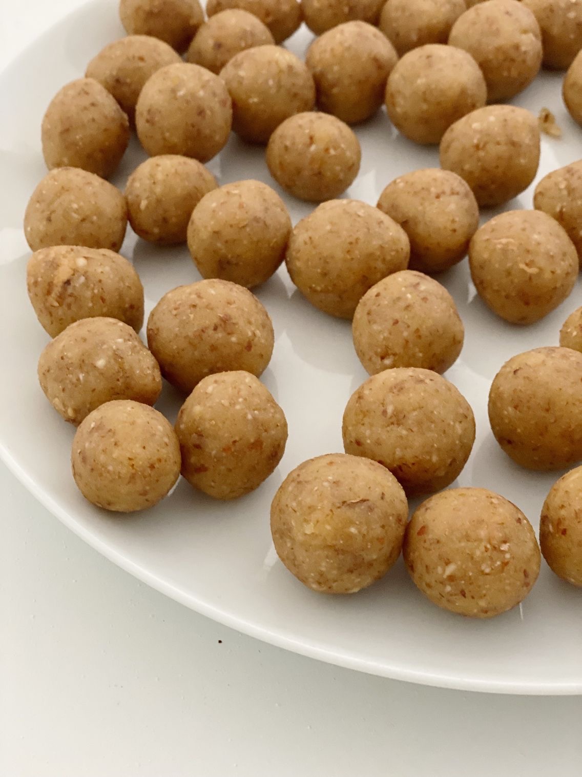 Marcipankuglerne på en hvid tallerken inden at de bliver overtrukken med chokolade.