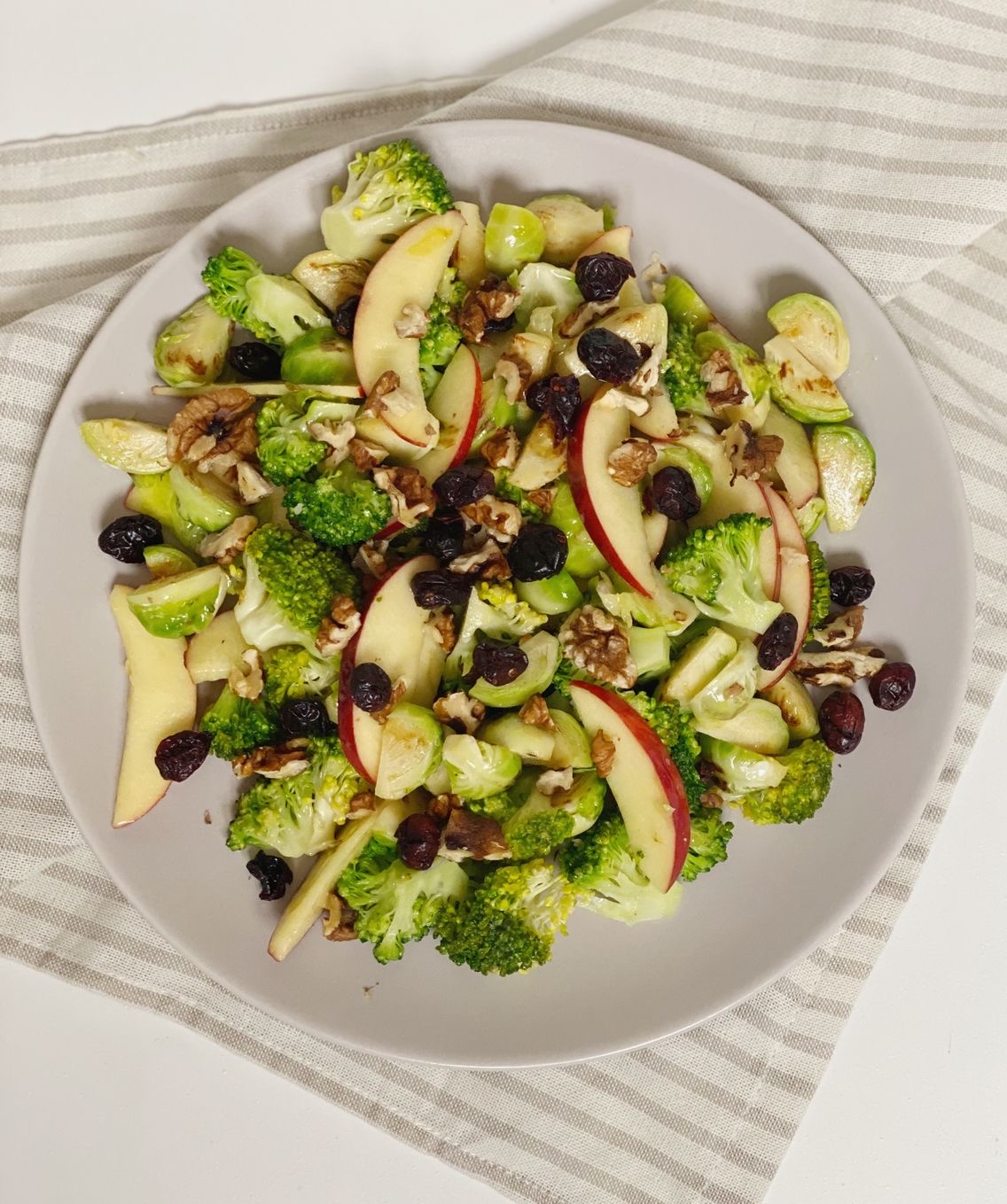 Broccolisalat med rosenkål på et hvidt fad. Set oppe fra så du kan se hele fadet med den lækre broccolisalat