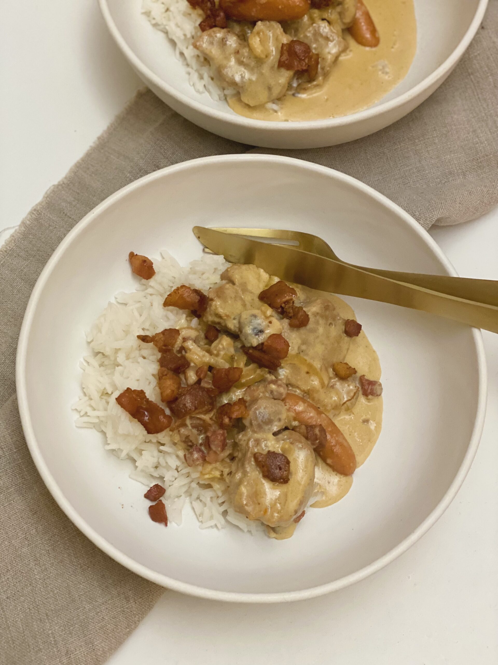 To portioner mørbrad ala creme serveret i dybe tallerkner med kogte ris til. Der er bestik af "guld" som ligger i tallerkenen