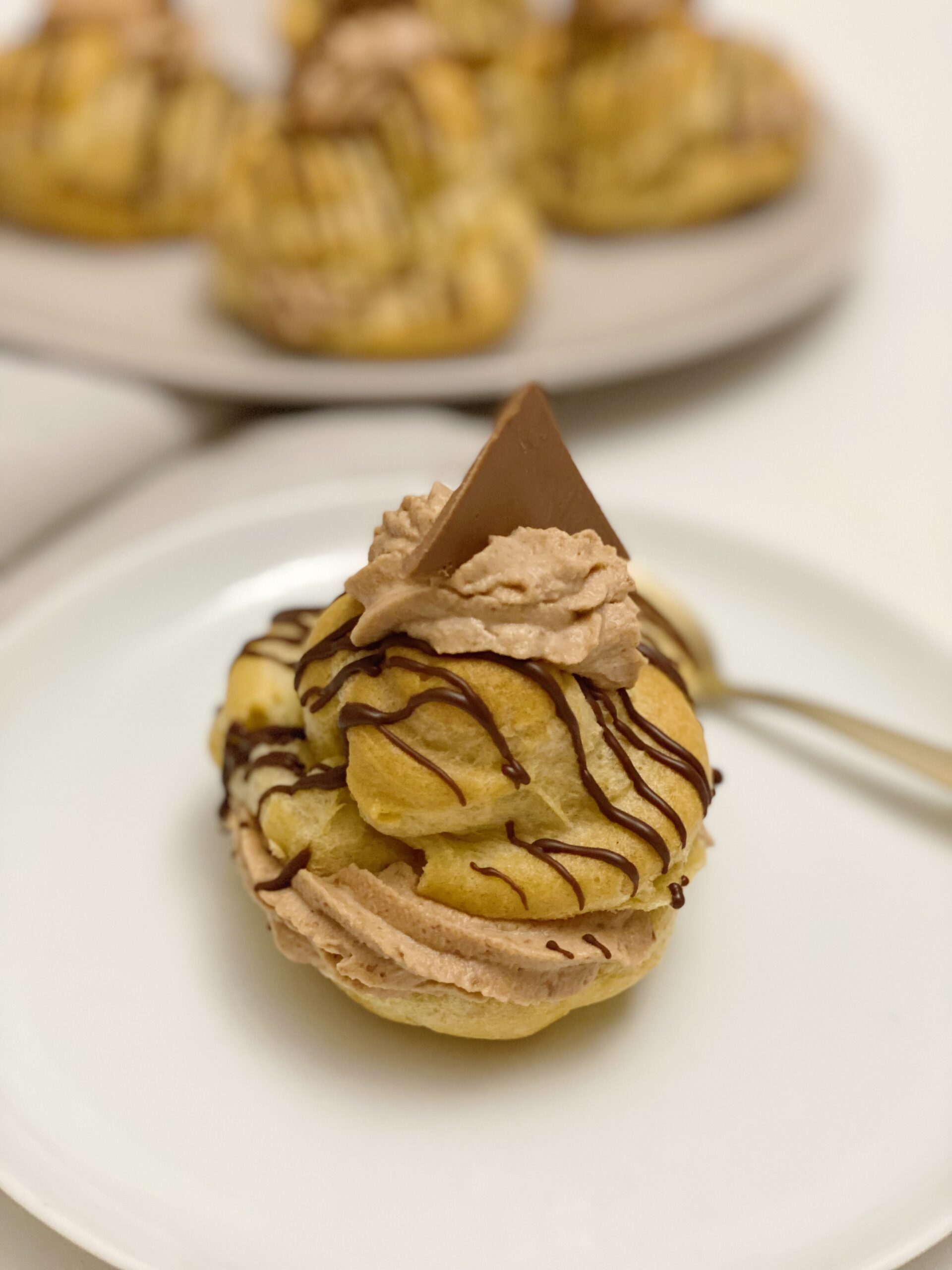 en fastelavnsbolle med nougatcreme og brombær som står på en tallerken og man kan de flere på en tallerken i baggrunden