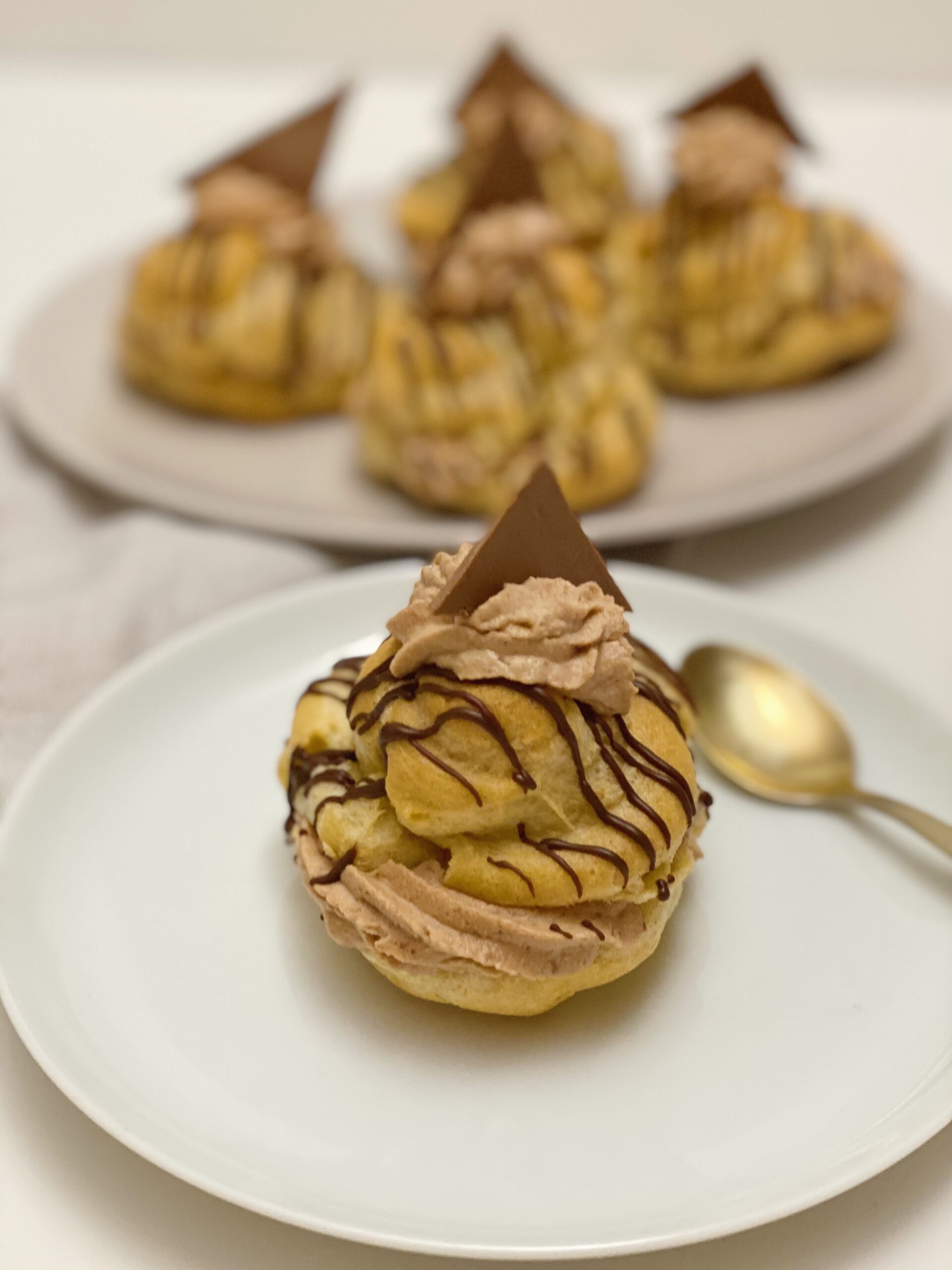 en fastelavnsbolle med nougatcreme og brombær som står på en tallerken og man kan de flere på en tallerken i baggrunden