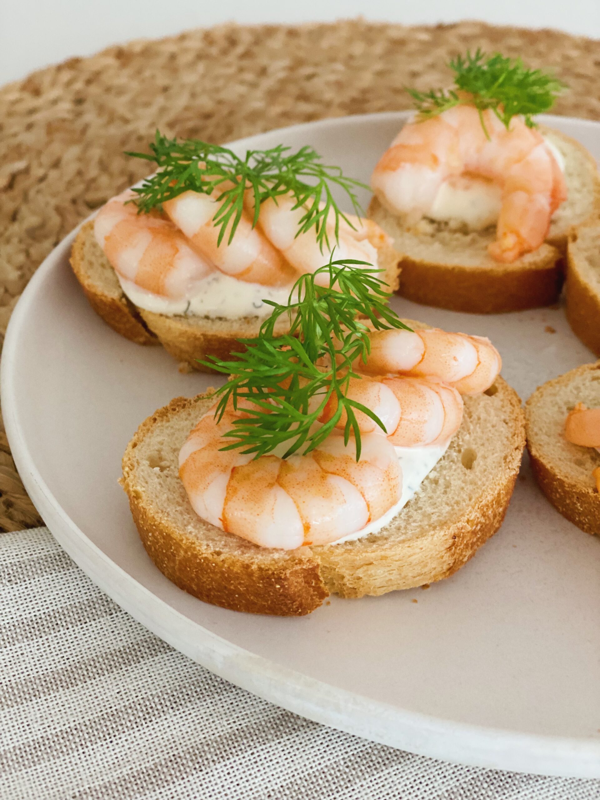 Små snacks med rejer og ostecreme set tæt på. De er på en hvid tallerken