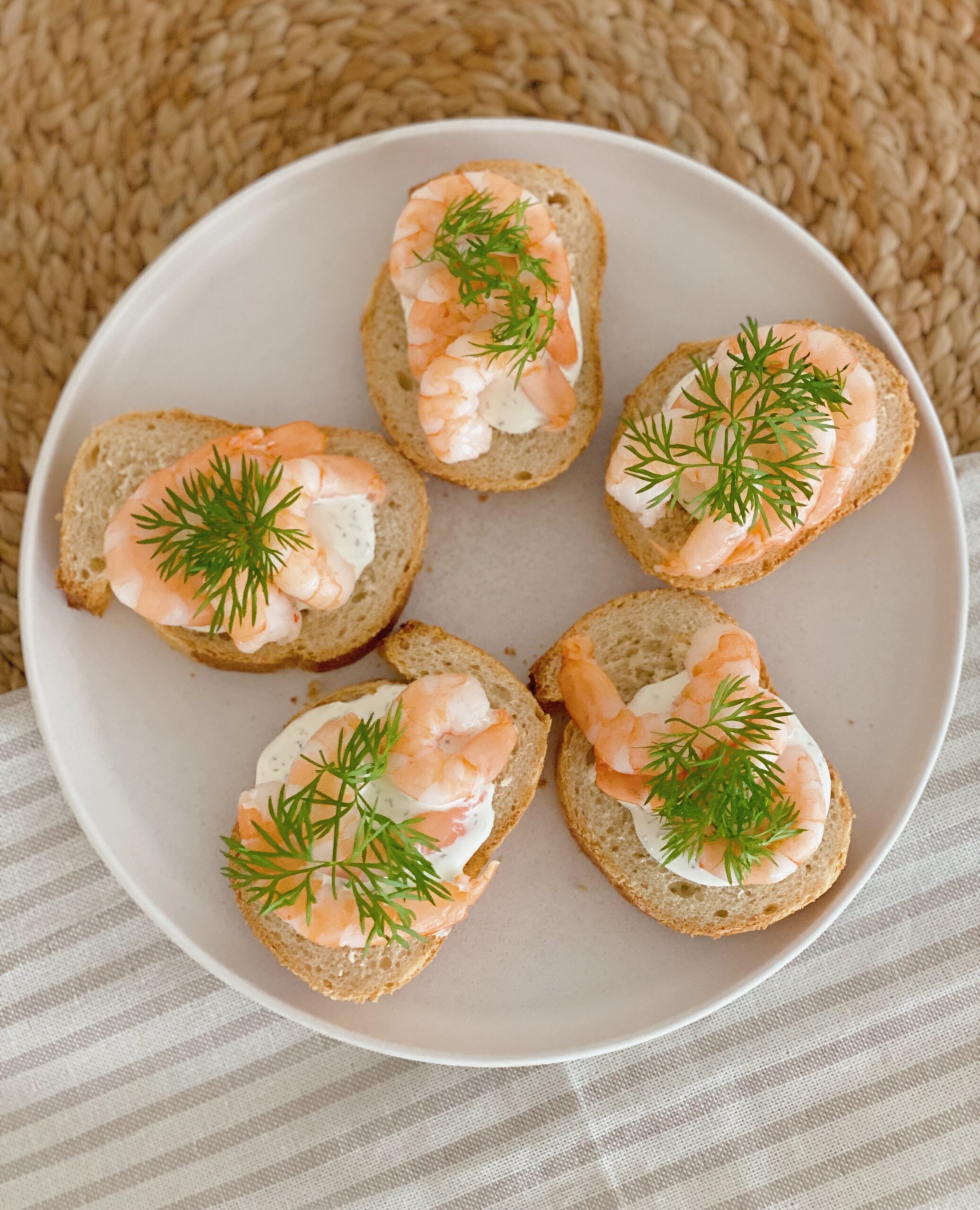 Små snacks med rejer og ostecreme set oppefra. De er på en hvid tallerken