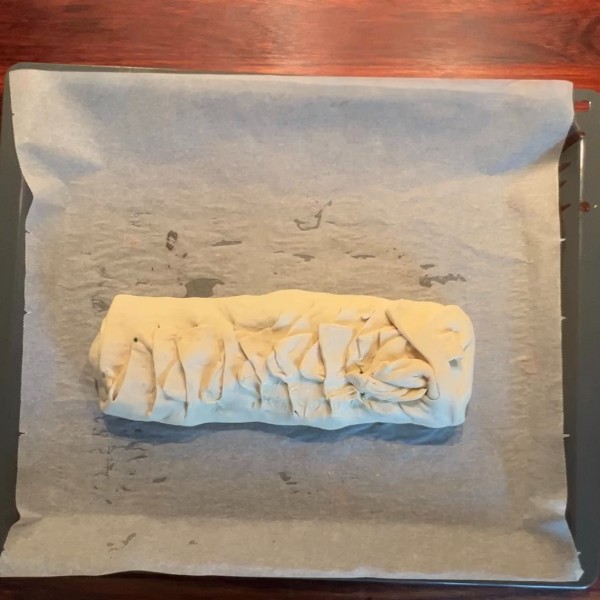 Den rå spanakopita stang inden at den bliver bagt, hvor man kan se hvordan den er flettet