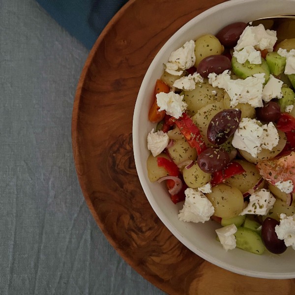 Græsk salat med nye kartofler, set tæt på og hvor man kun ser halvdelen af skålen