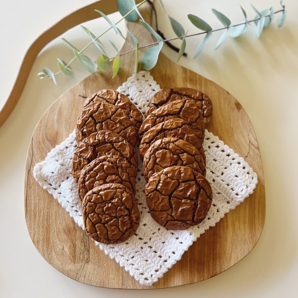 Chewy chokolade cookies på en hæklet hvid serviet på et træspækbræt set oppefra